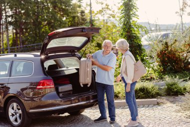 Bagajları olan yaşlı çift otele gidiyor. 