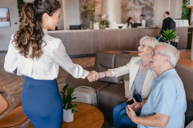 Yaşlı çift otel yöneticisiyle tokalaşıyor. 