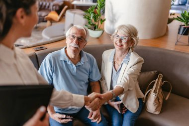 Yaşlı çift otel yöneticisiyle tokalaşıyor. 