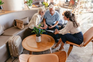 Mutlu bayan yönetici müşterilerle konuşuyor. Otelde olgun bir çift. 