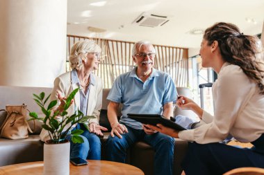 Mutlu bayan yönetici müşterilerle konuşuyor. Otelde olgun bir çift. 