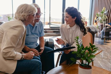 Gülümseyen yaşlı çift otel yöneticisiyle konuşuyor. 