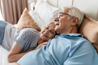 Gülümseyen ve yatakta uzanan mutlu yaşlı çift..