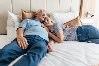 Gülümseyen ve yatakta uzanan mutlu yaşlı çift..