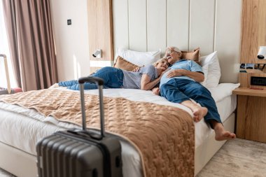 Otel odasında yaşlı bir adam ve kadın var..
