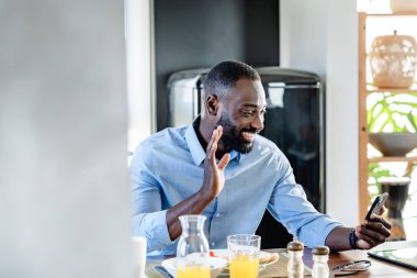 Genç Afrikalı Amerikalı bir adam cep telefonuyla video görüşmesi yapıyor.