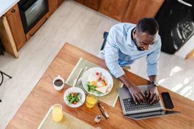 Laptoplu Afro-Amerikan adam kahvaltı yapıyor. 