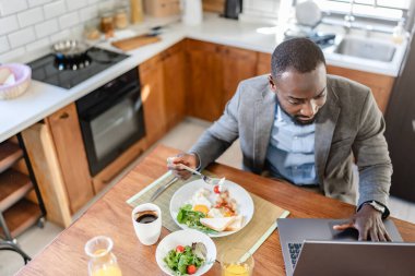 Laptoplu Afro-Amerikan adam kahvaltı yapıyor. 