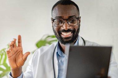 Afro-Amerikan doktor klinikte tablet kullanıyor.