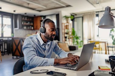 Ofiste çalışan, kulaklıklı yakışıklı genç adam.