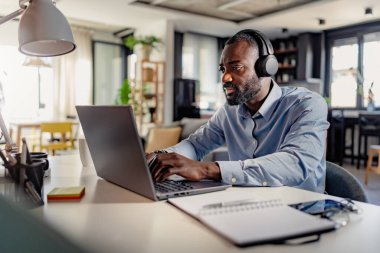 Bilgisayarda çalışan kulaklıklı genç bir erkek. 