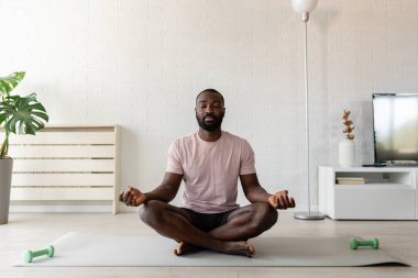 Afro-Amerikan adam evde meditasyon yapıyor. 