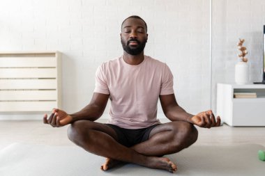 Afro-Amerikan adam evde meditasyon yapıyor. 