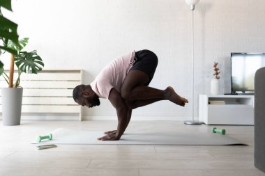 Afrika kökenli Amerikalı adam dambıllarla egzersiz yapıyor.