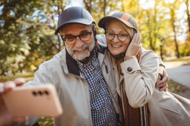 Sonbahar parkında selfie çeken olgun bir çift. 