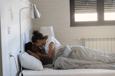 Mutlu çift yatak odasında yatıyor, sarılıyor ve gülümsüyor. 