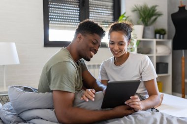Yatakta dijital tabletli Afro-Amerikan çift 