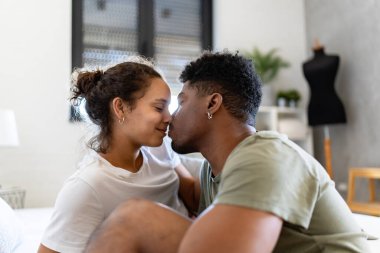 Genç çift evdeki kanepede öpüşüyor. 