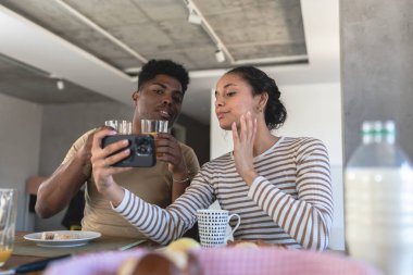 Mutlu, genç, çok ırklı çift cep telefonu kullanarak selfie çekiyor. 
