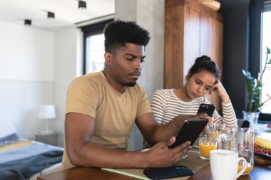 Genç bir çift mutfakta akıllı telefon kullanıyor.