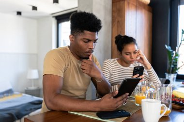 Genç bir çift mutfakta akıllı telefon kullanıyor.