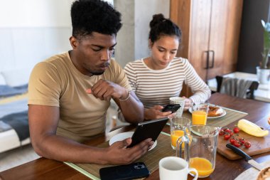 Genç bir çift mutfakta akıllı telefon kullanıyor.