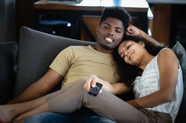 Kanepede uzanmış ve oturma odalarında televizyon izleyen sıradan bir çift..