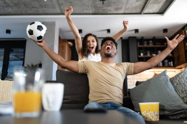 Mutlu çift evde, evde, oturma odasında futbol maçı izliyor. 