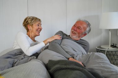 Mutlu yaşlı çift evde yatakta yatıyor..