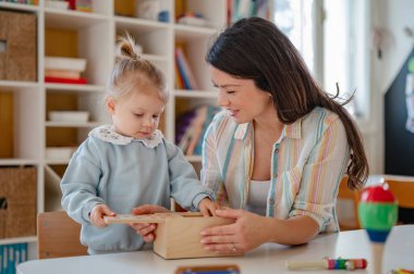 Anaokulunda öğretmenle oynayan tatlı küçük kız. 