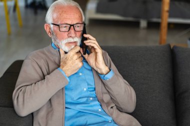 Evde cep telefonuyla konuşan olgun bir iş adamı..