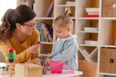 Küçük kız ve öğretmeni birlikte oynuyorlar. 