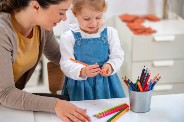 Öğretmen ve kız birlikte çiziyorlar. 