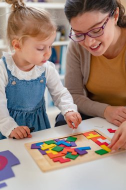 Öğretmen ve kız tahta parçalarıyla oynuyorlar. 