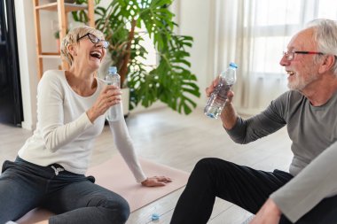 Olgun erkek ve kadın içme suyu eğitiminden sonra yerde oturuyorlar. 