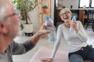 Olgun erkek ve kadın içme suyu eğitiminden sonra yerde oturuyorlar. 