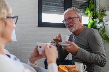 Mutlu olgun çift evde kahve içiyor. 