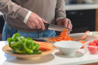 Adam mutfakta sebze doğruyor. 