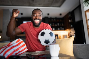 Heyecanlı adam evdeki kanepede maç izliyor. 