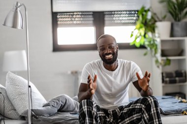 Yakışıklı Afro-Amerikan adam yatakta oturuyor. 
