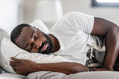 Huzurlu bir adam, sabah vakti yumuşak yastıkta rahat bir şekilde uyuyor.