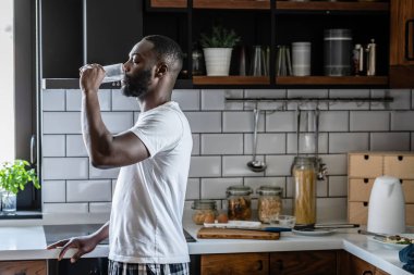 Afro-Amerikan adam camdan su içiyor. 