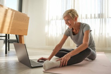 Dizüstü bilgisayarı olan son sınıf öğrencisi evde egzersiz yapıyor. 