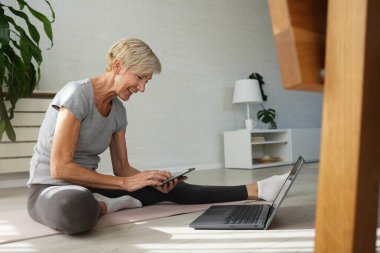 İnternette egzersiz yapan olgun, son sınıf öğrencisi bir kadın. 