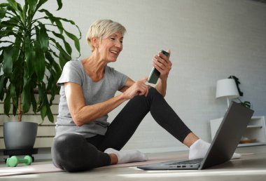 İnternette egzersiz yapan olgun, son sınıf öğrencisi bir kadın. 