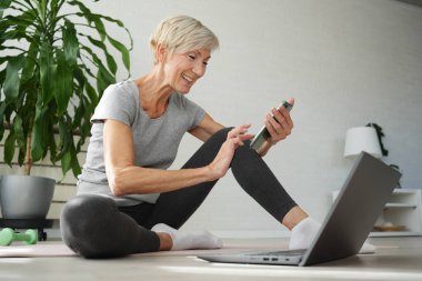 İnternette egzersiz yapan olgun, son sınıf öğrencisi bir kadın. 