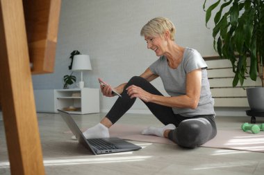 İnternette egzersiz yapan olgun, son sınıf öğrencisi bir kadın. 