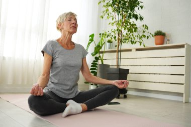 Evde yoga yapan son sınıf öğrencisi bir kadın. 