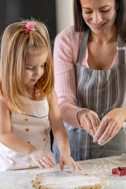 Mutlu anne ve kız mutfakta birlikte kurabiye yapıyorlar.