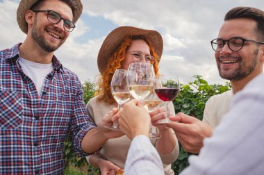 Gülümseyen arkadaşlar üzüm bağları toplanırken dışarıda şarap kadehlerini tokuşturuyorlar.
